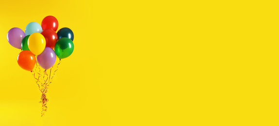 Image of Bunch of bright balloons on yellow background, space for text. Banner design 