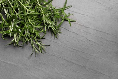 Photo of Aromatic green rosemary sprigs on gray table, top view. Space for text
