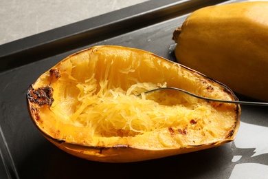 Photo of Baking sheet with cooked spaghetti squash and fork on table, closeup