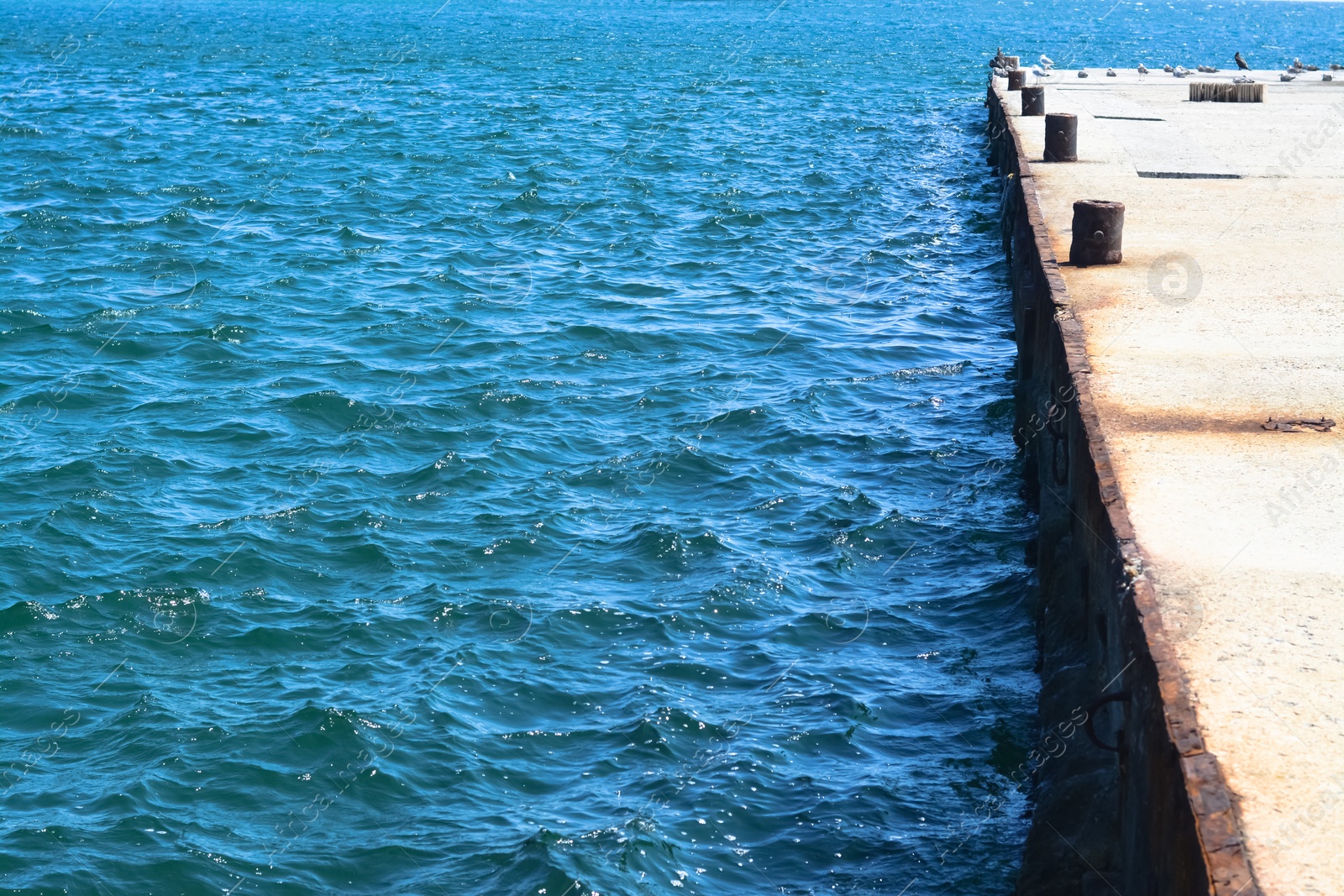 Photo of Beautiful concrete pier in sea on sunny day, space for text