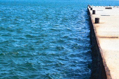 Photo of Beautiful concrete pier in sea on sunny day, space for text