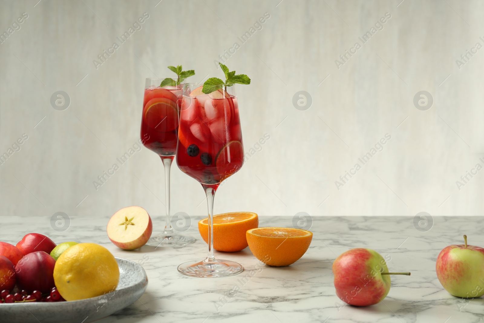 Photo of Glasses of Red Sangria and fruits on white marble  table