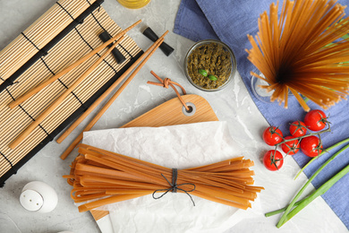 Flat lay composition with uncooked buckwheat noodles on light grey table