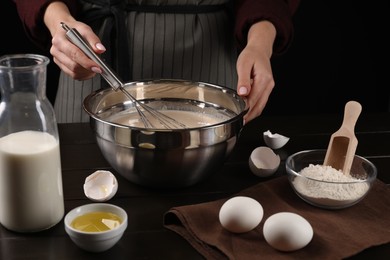 Photo of Woman making dough with whisk in bowl at table, closeup