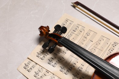 Photo of Violin, bow and music sheets on grey marble table. Space for text