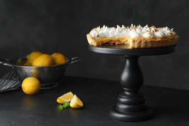 Photo of Stand with delicious lemon meringue pie on dark grey table, space for text