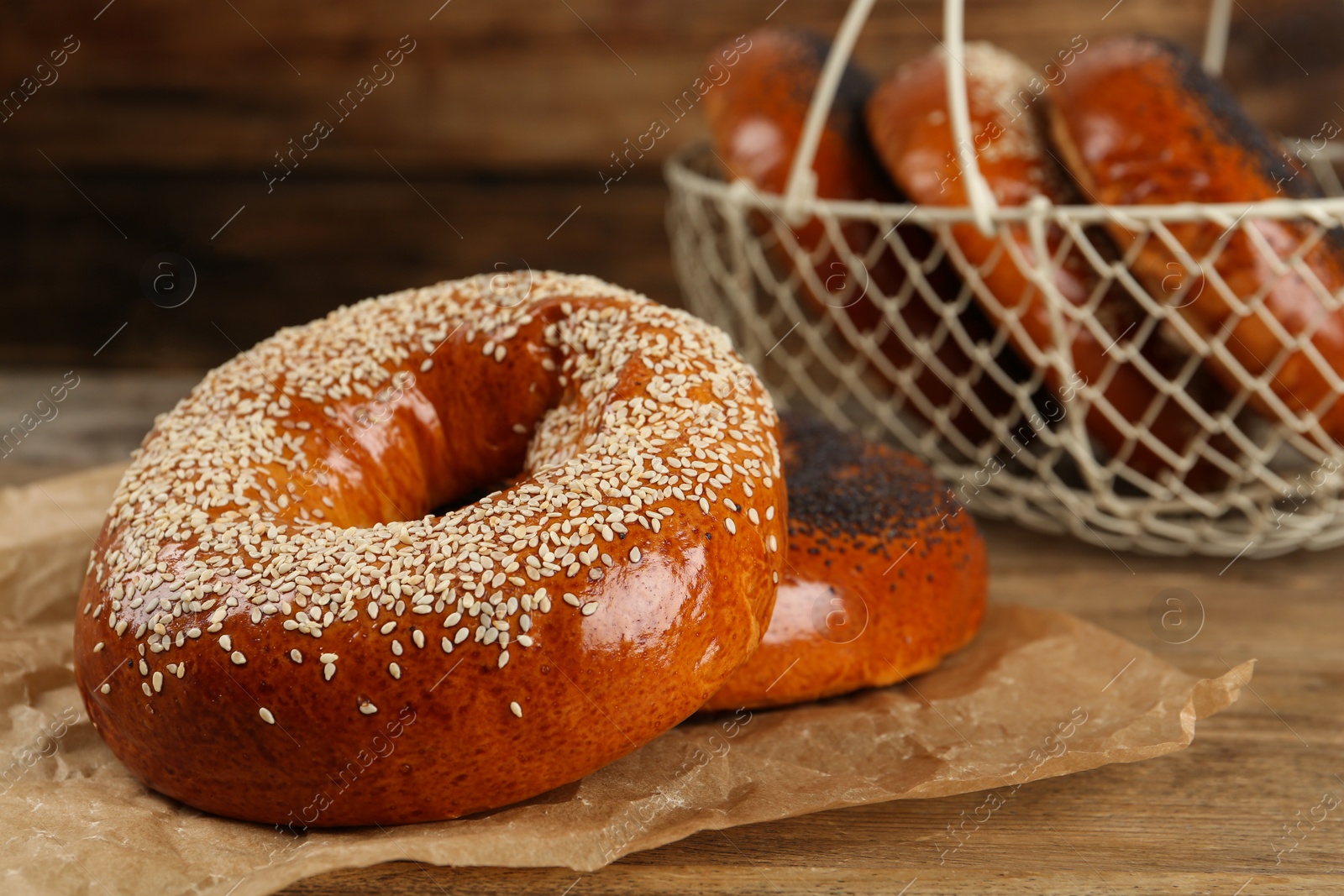 Photo of Delicious fresh bagels with poppy and sesame seeds on wooden table