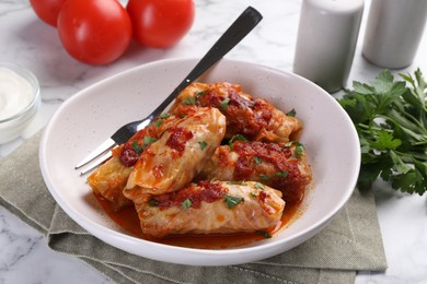 Photo of Delicious stuffed cabbage rolls cooked with homemade tomato sauce on white marble table, closeup