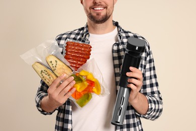 Photo of Man holding sous vide cooker and different food in vacuum packs on beige background, closeup