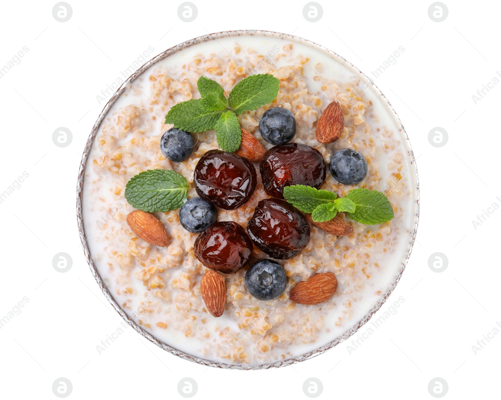 Photo of Tasty wheat porridge with milk, dates, blueberries and almonds in bowl isolated on white, top view