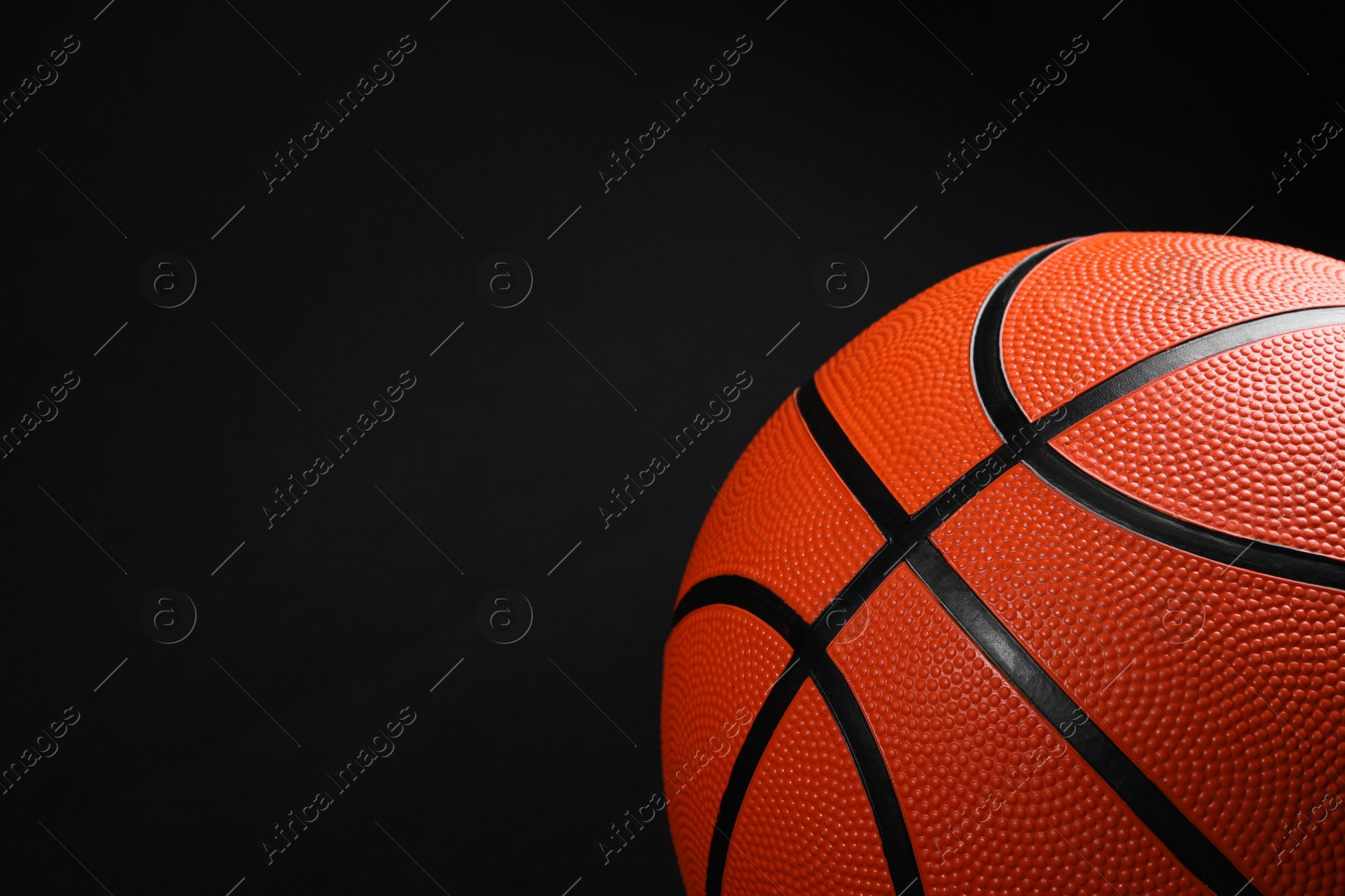 Photo of One basketball ball on black background, closeup. Space for text