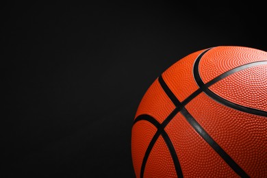 Photo of One basketball ball on black background, closeup. Space for text