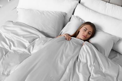 Beautiful woman sleeping in comfortable bed with silky linens, above view