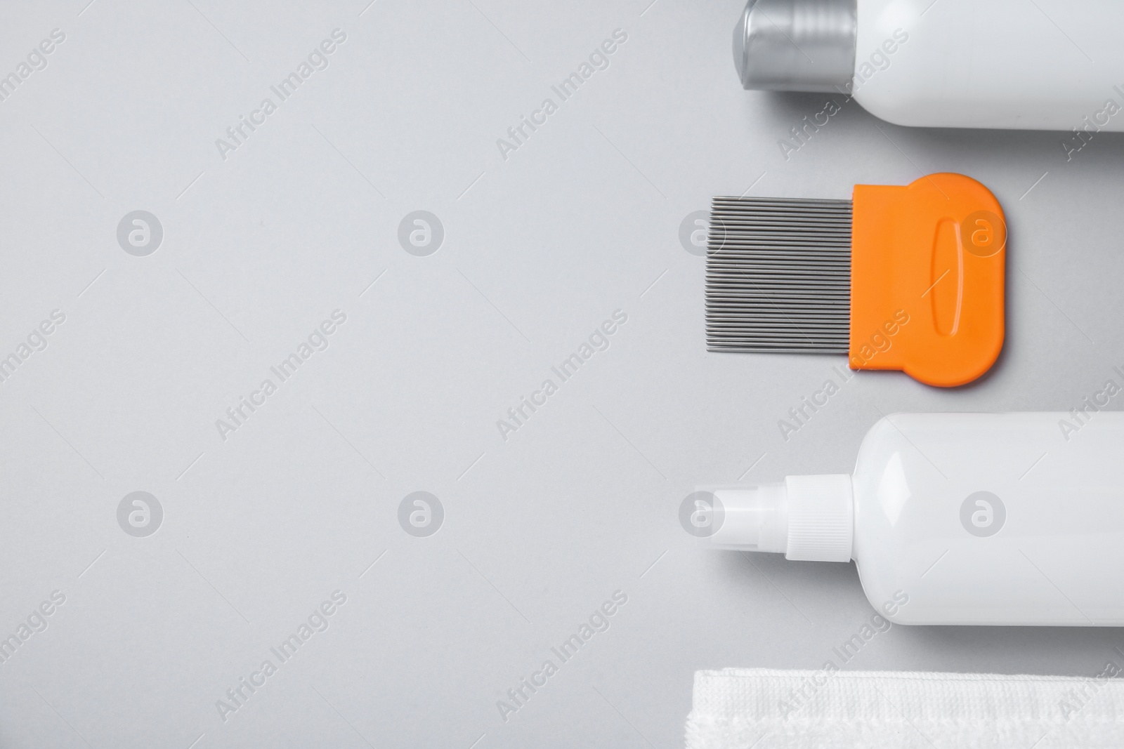 Photo of Products for anti lice treatment, metal comb and towel on light grey background, flat lay. Space for text