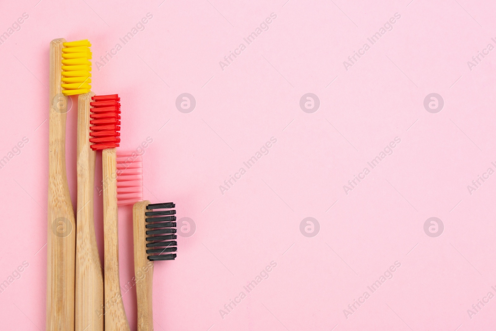 Photo of Toothbrushes made of bamboo on pink background, flat lay. Space for text