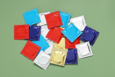 Photo of Packaged condoms on light green background, top view. Safe sex