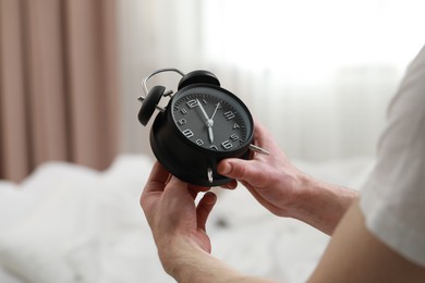 Photo of Man with alarm clock in bedroom, closeup of hands