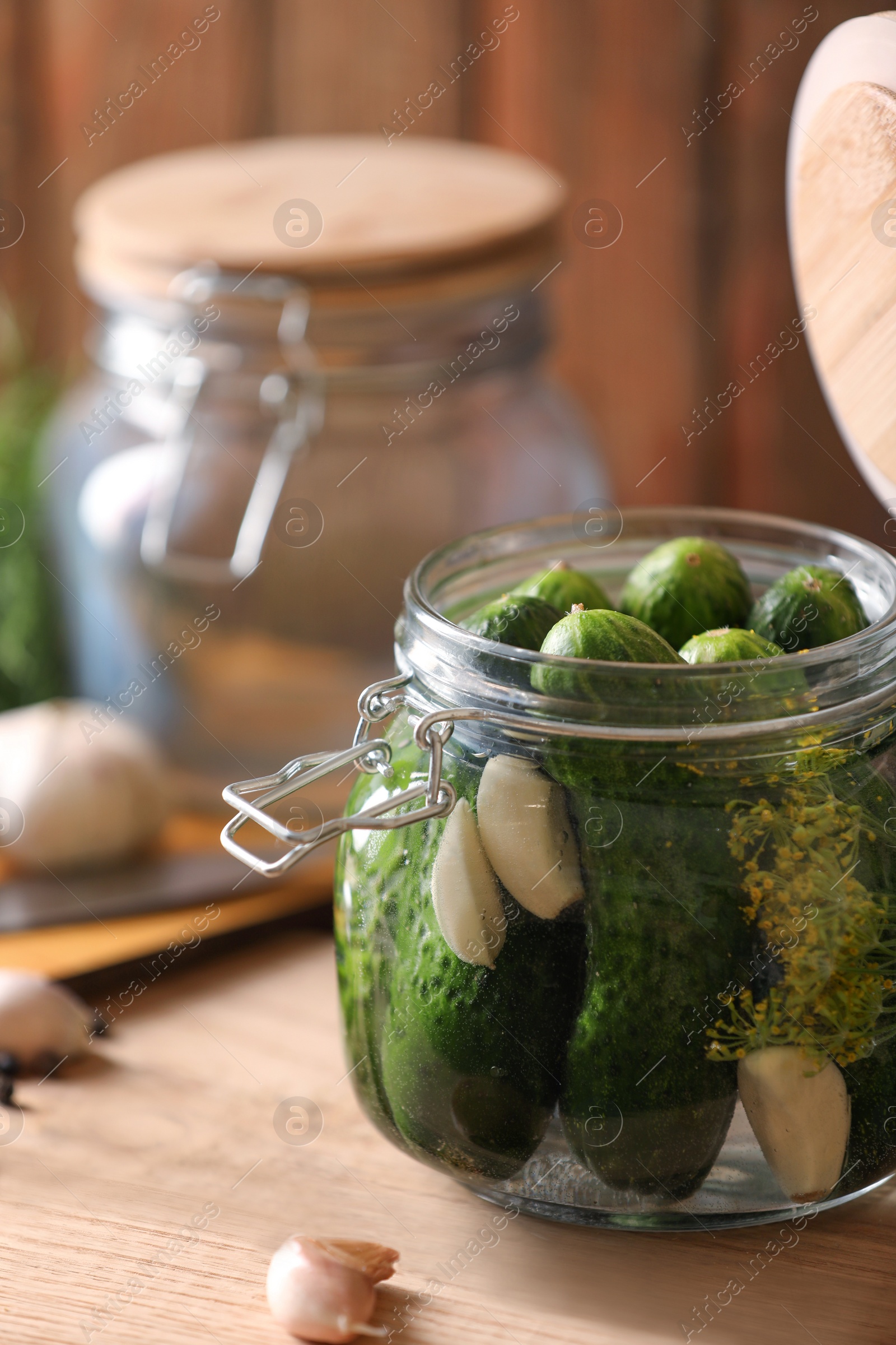 Photo of Glass jar with fresh cucumbers and other ingredients on wooden table. Canning vegetable