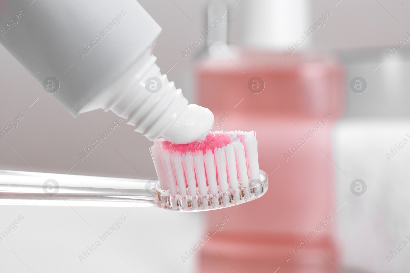 Photo of Applying paste on toothbrush near mouthwash, closeup