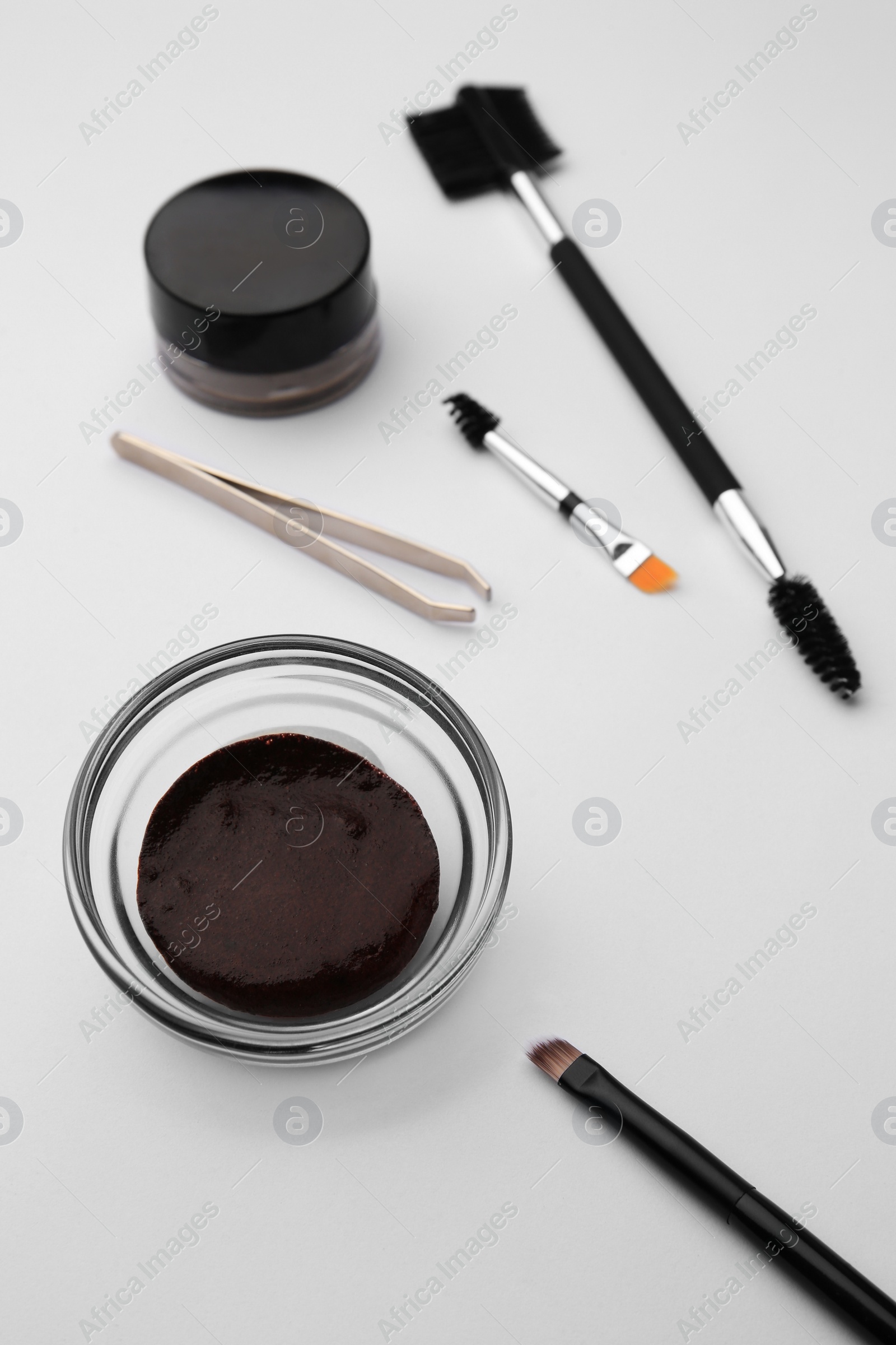 Photo of Eyebrow henna and professional tools on white background, closeup