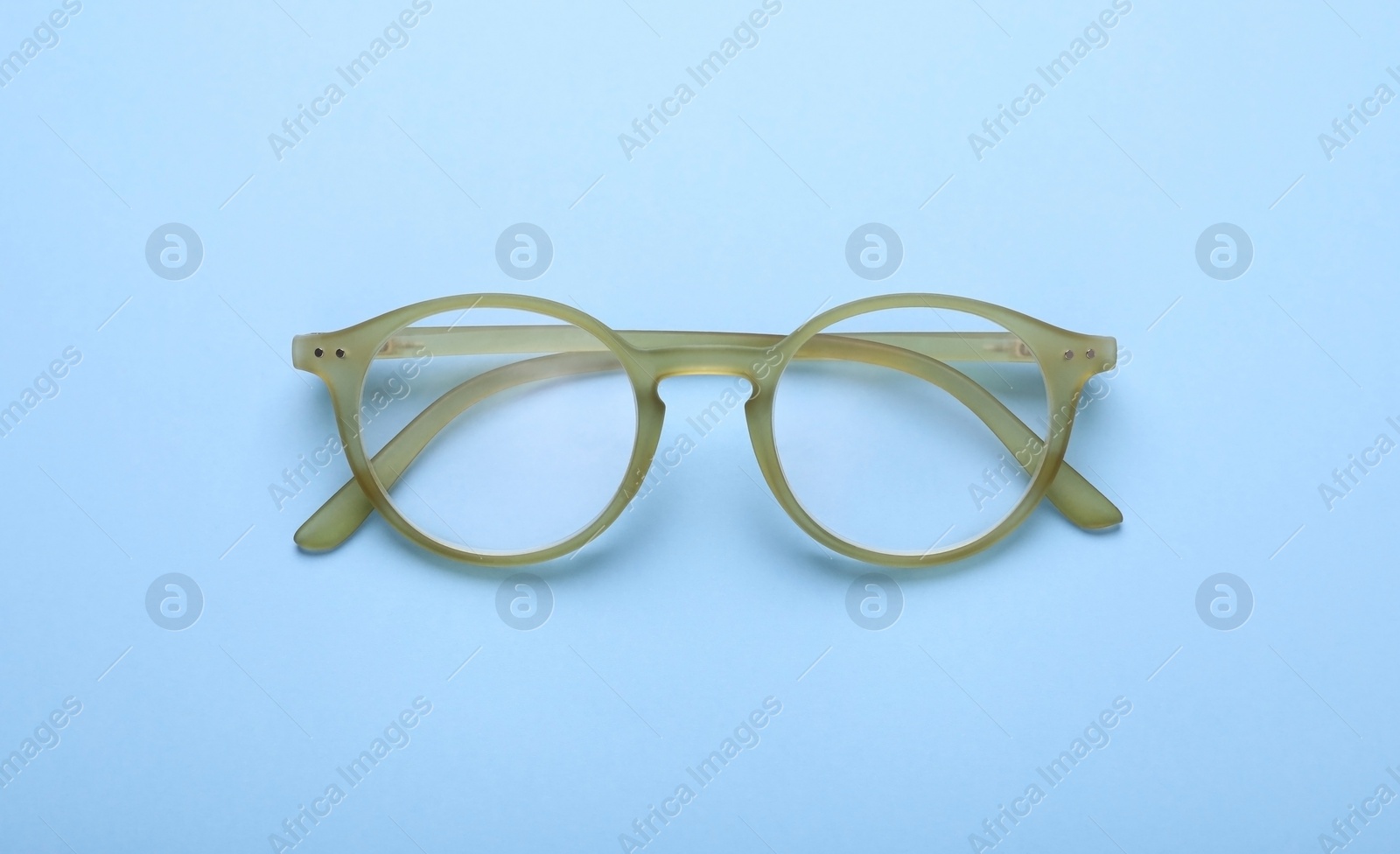 Photo of Glasses with corrective lenses on light blue background, top view