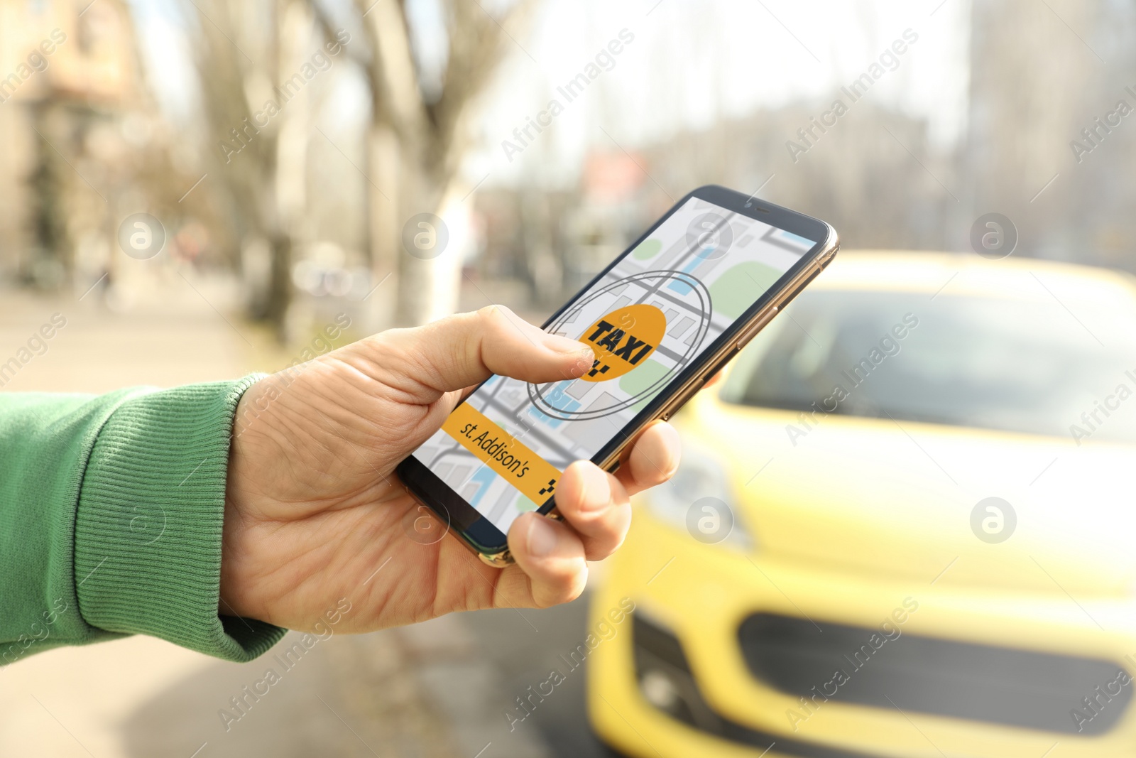 Photo of Man ordering taxi with smartphone on city street, closeup