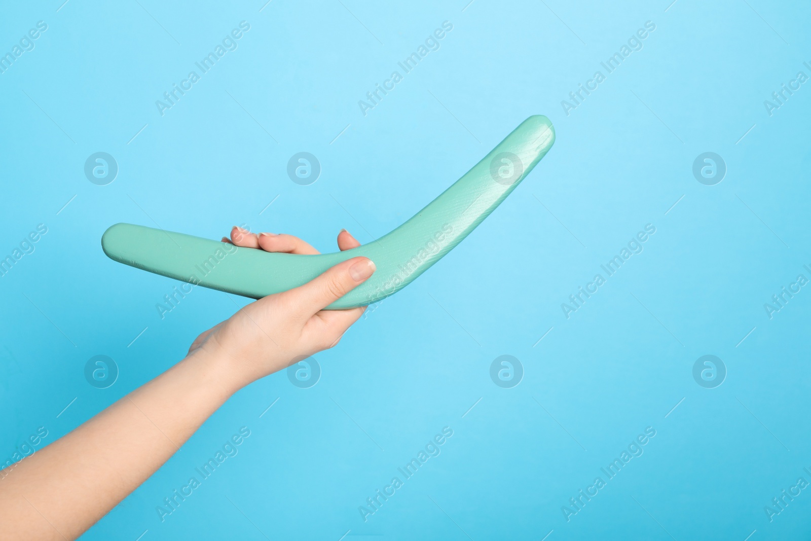 Photo of Woman holding boomerang on light blue background, closeup. Space for text