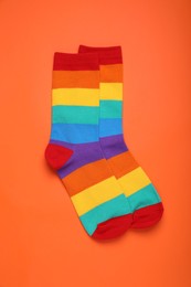 Photo of Rainbow socks on orange background, flat lay. LGBT pride