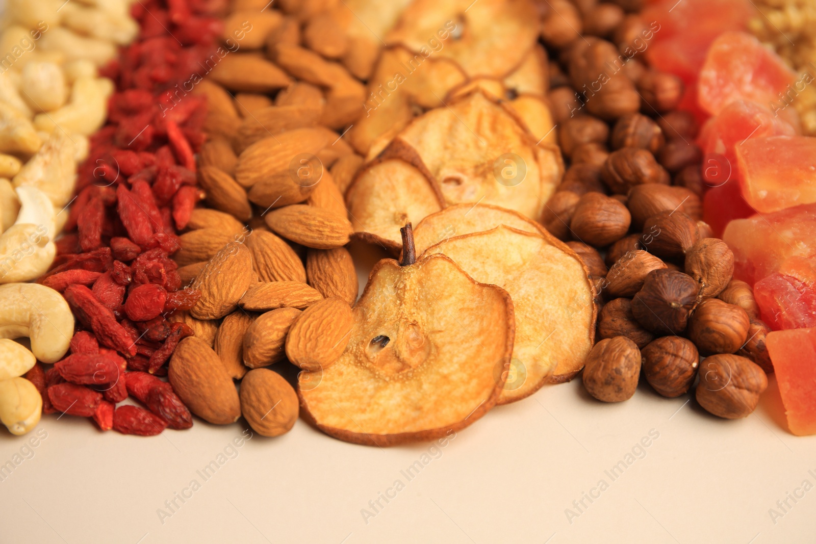 Photo of Mix of delicious dried nuts and fruits on beige background, closeup