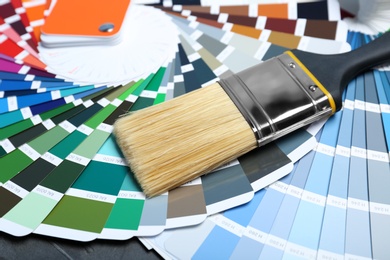 Photo of Brush and paint color palette samples on table, closeup