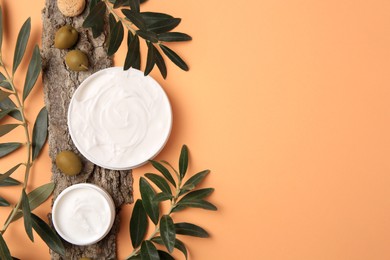 Photo of Flat lay composition with jars of cream and olives on pale orange background. Space for text