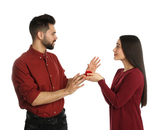 Young man rejecting engagement ring from girlfriend on white background