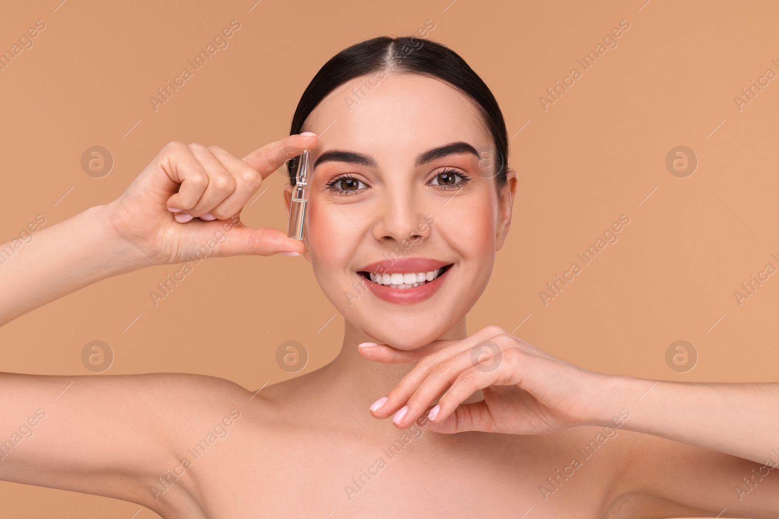 Photo of Beautiful young woman holding skincare ampoule on beige background