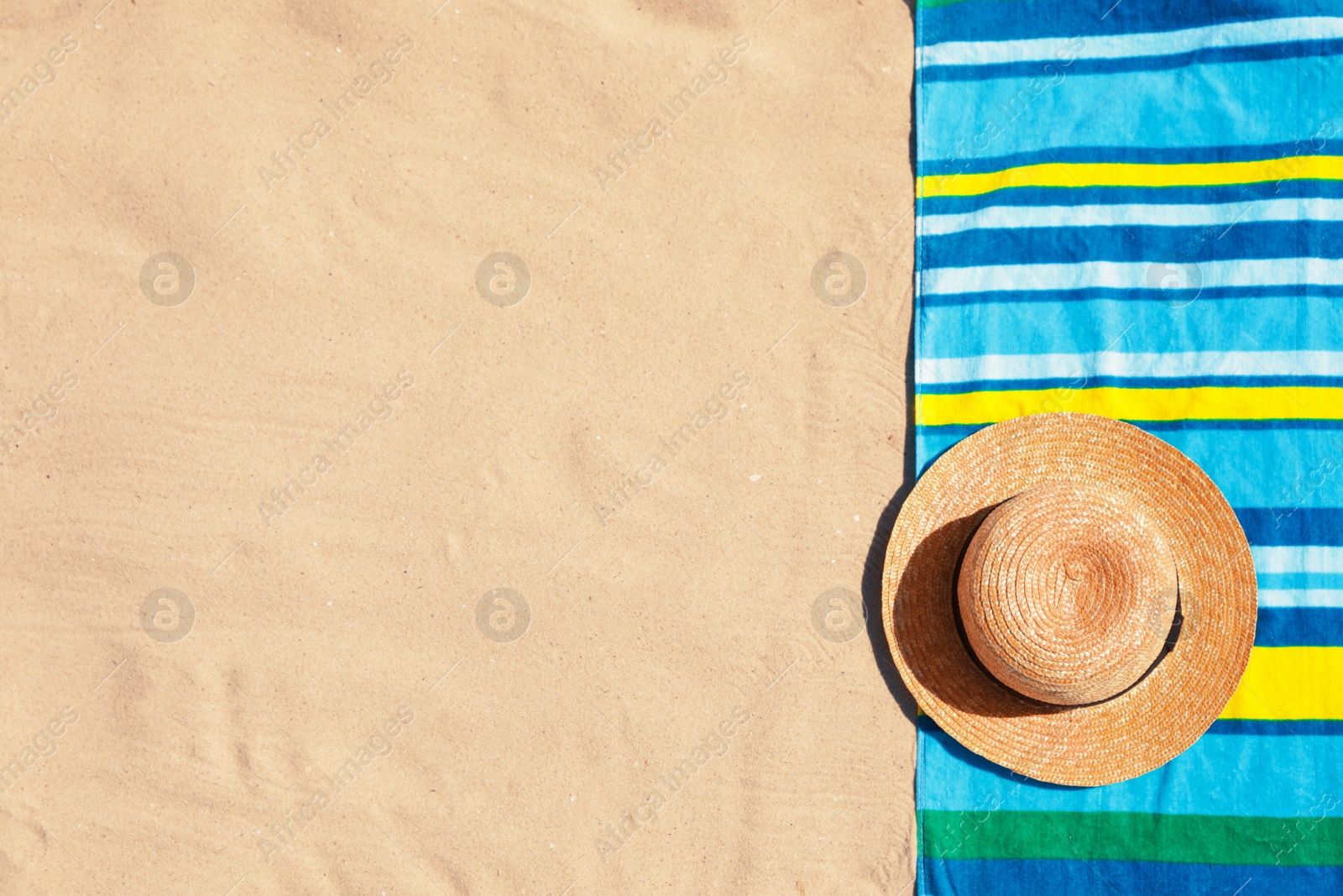 Photo of Stylish hat and beach towel on sand, top view. Space for text