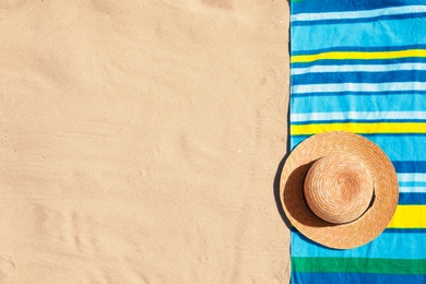 Photo of Stylish hat and beach towel on sand, top view. Space for text