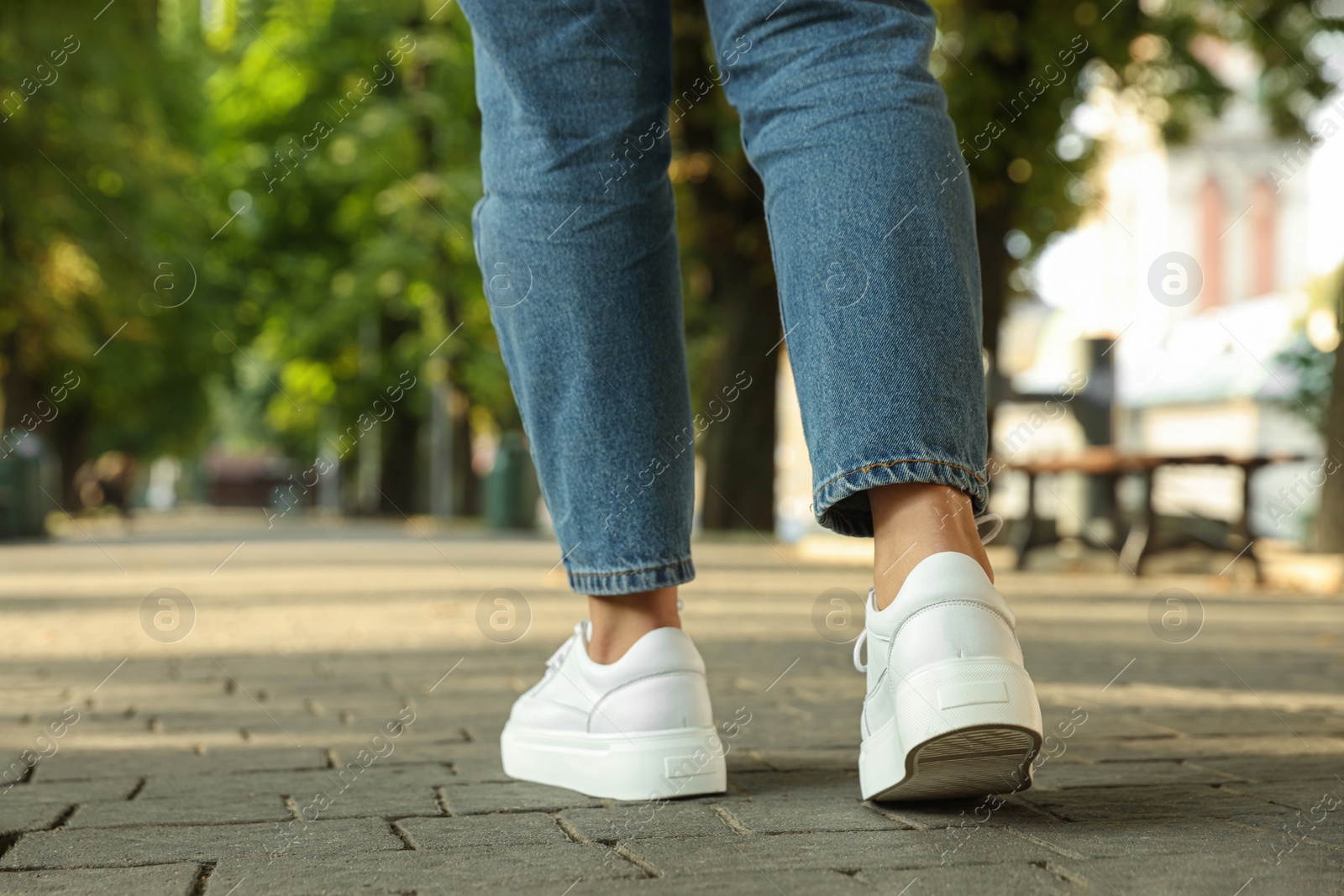 Photo of Woman in stylish sneakers walking on city street, closeup