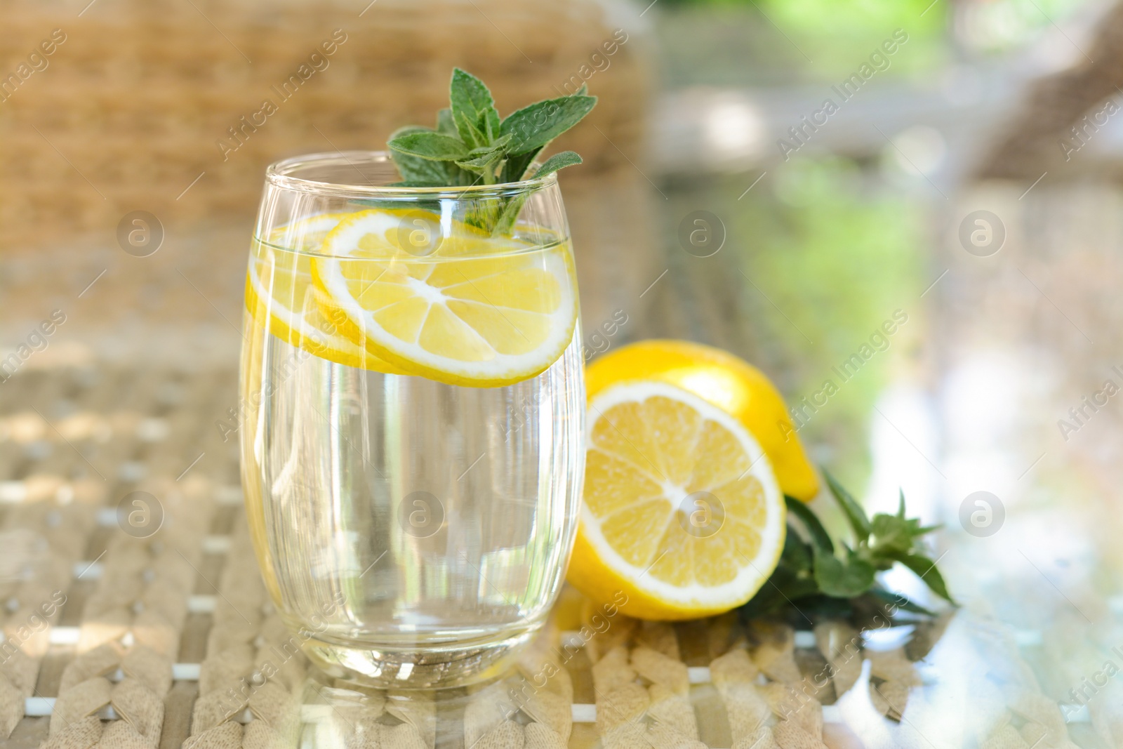 Photo of Refreshing water with lemon and mint on glass table