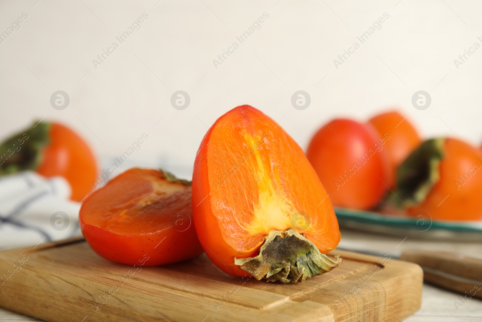 Photo of Tasty ripe persimmon on wooden board, closeup