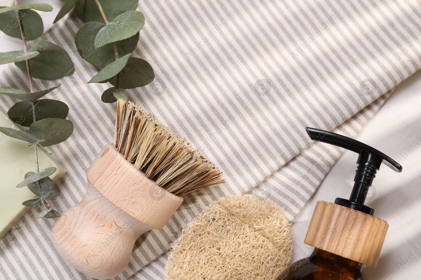 Photo of Cleaning brush, sponge, dispenser and eucalyptus leaves on table, top view