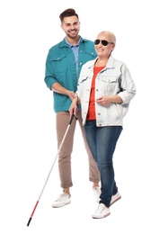 Photo of Young man helping blind person with long cane on white background