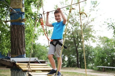 Photo of Little boy climbing in adventure park. Summer camp