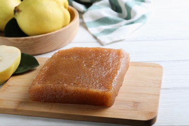 Photo of Delicious quince paste on white wooden table, closeup