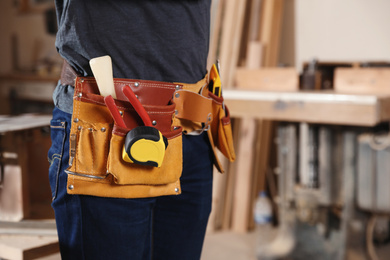 Photo of Professional carpenter with tools in workshop, closeup. Space for text