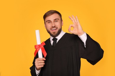 Happy student with diploma on yellow background