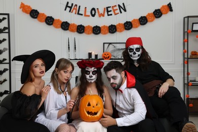 Photo of Group of people in scary costumes with carved pumpkin indoors. Halloween celebration