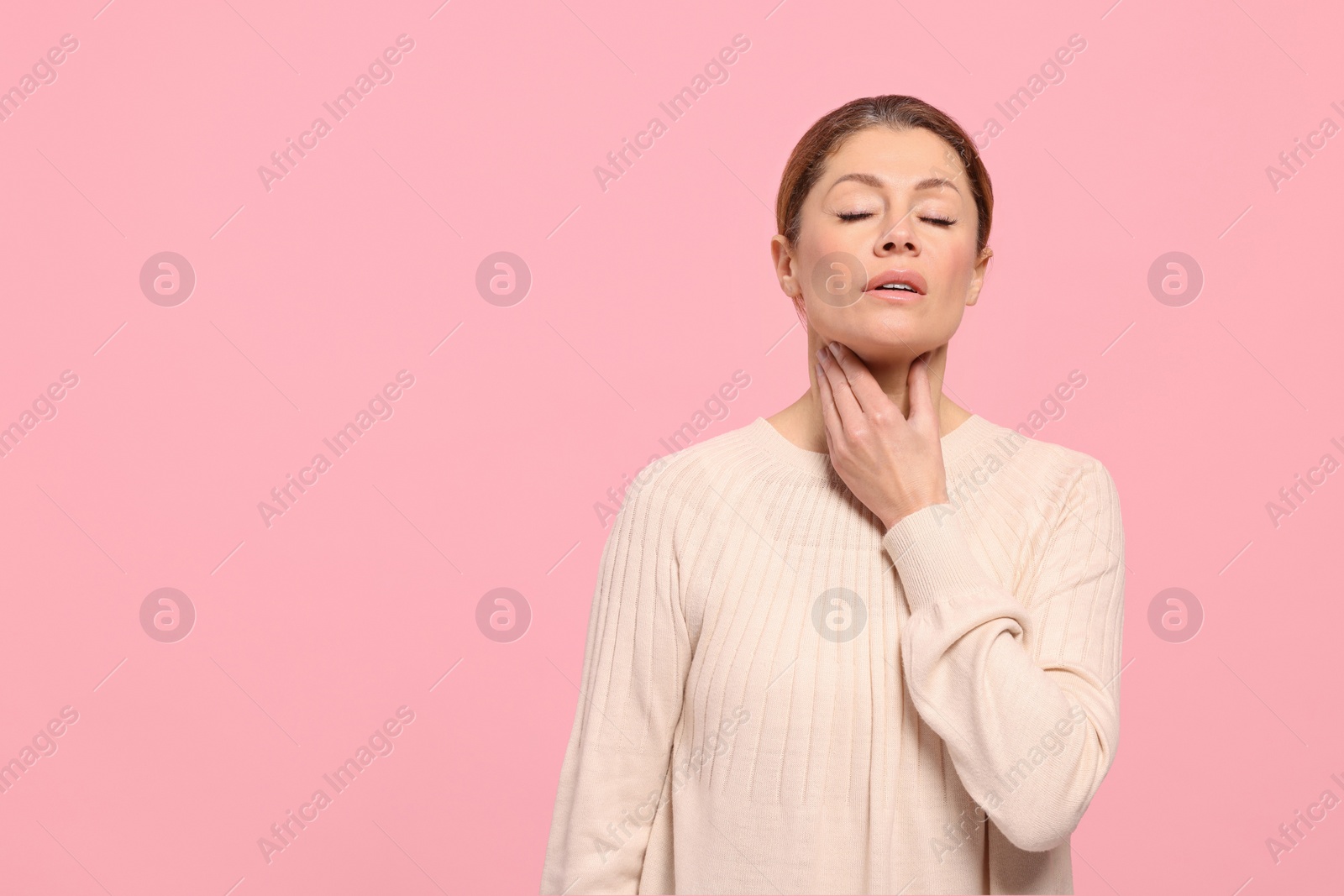 Photo of Woman suffering from sore throat on pink background. Space for text