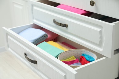 Chest of drawers with different folded clothes indoors