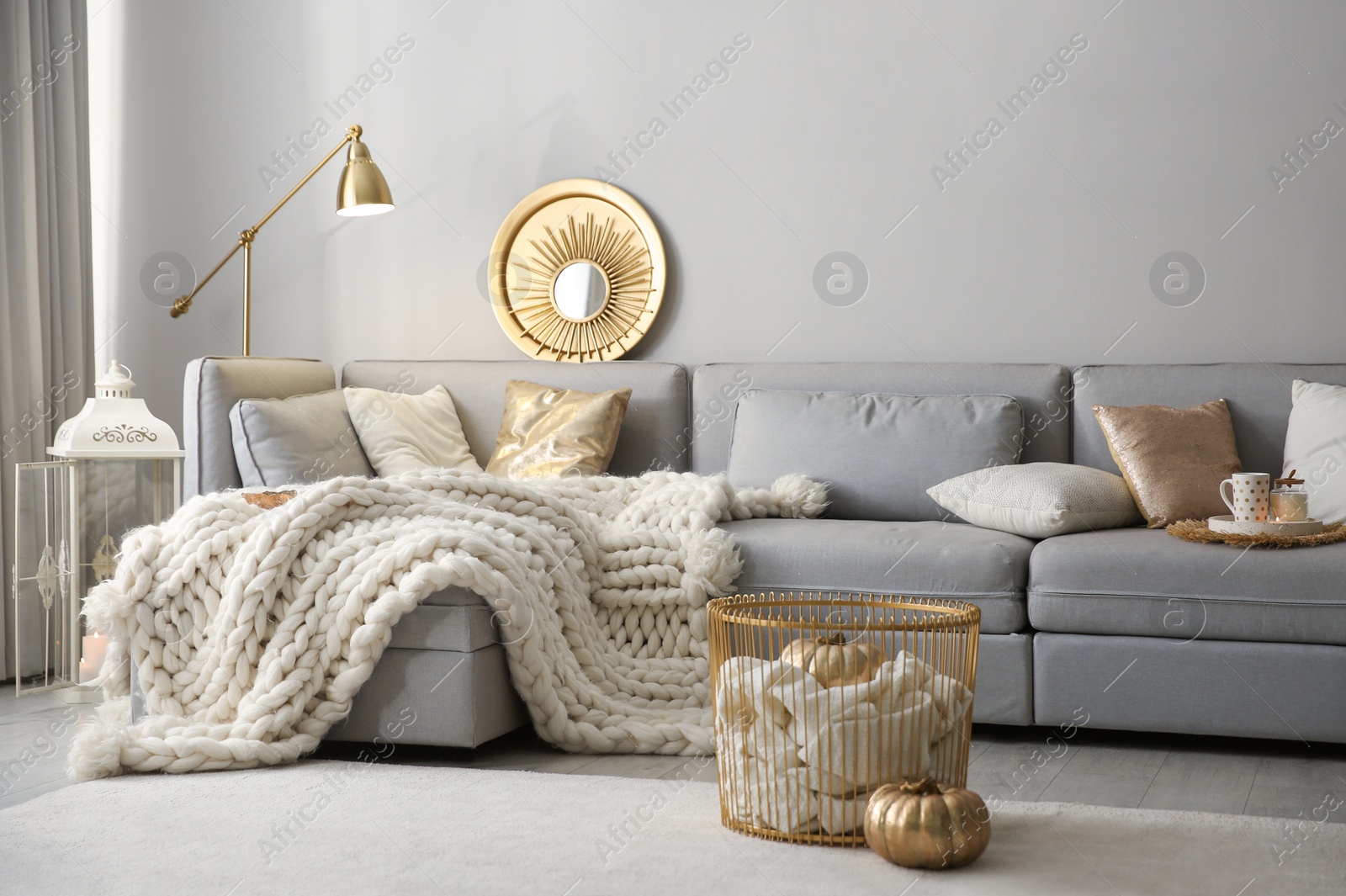 Photo of Cozy living room interior with knitted blanket on comfortable sofa