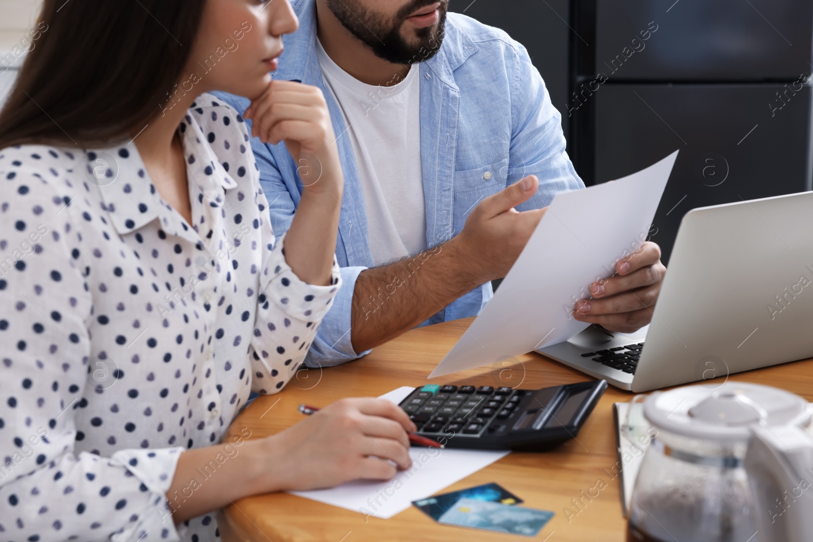 Photo of Young couple discussing family budget in kitchen, closeup