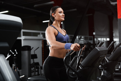 Young woman working out on elliptical trainer in modern gym